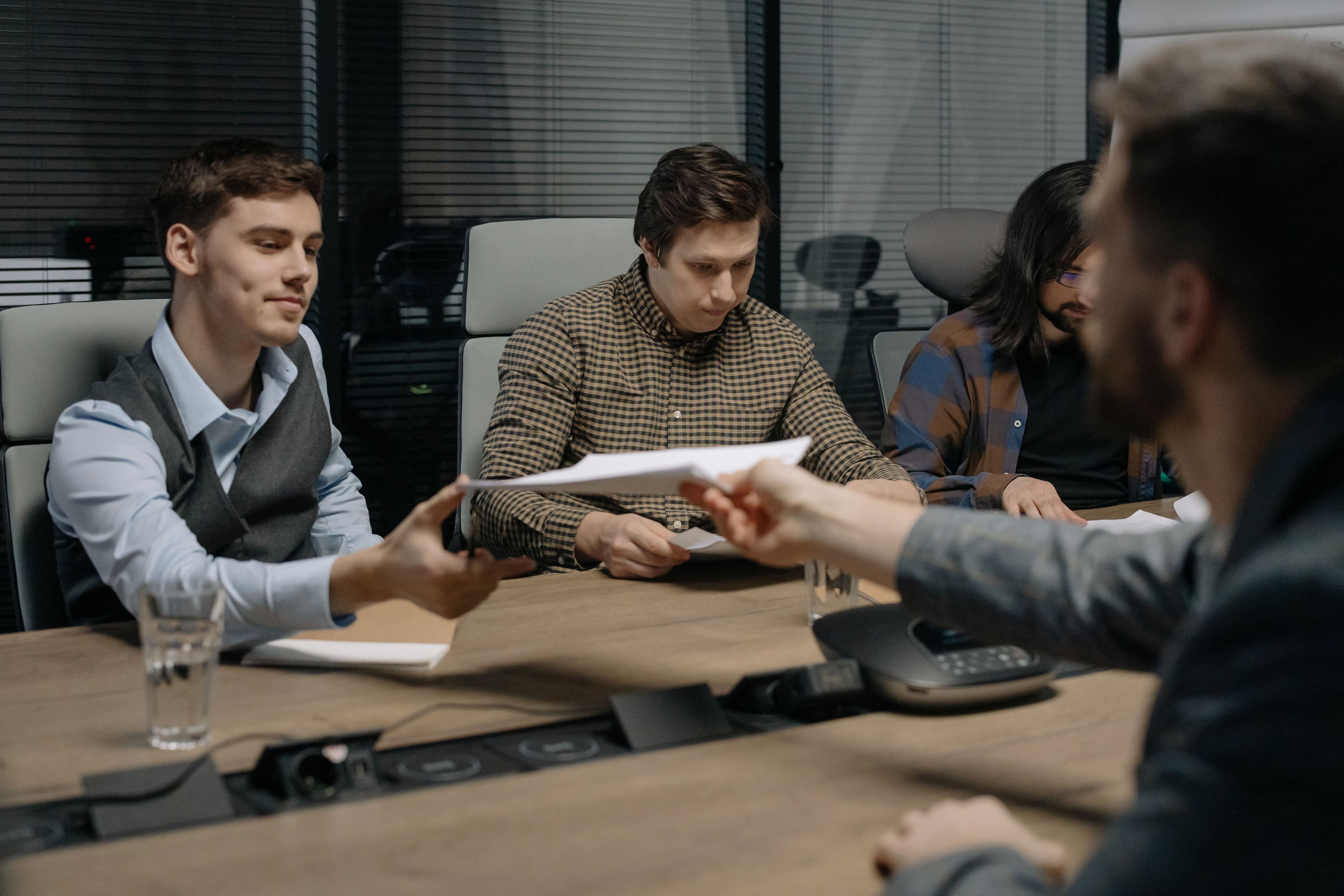 A candidate handing a printed resume across a conference table during an interview