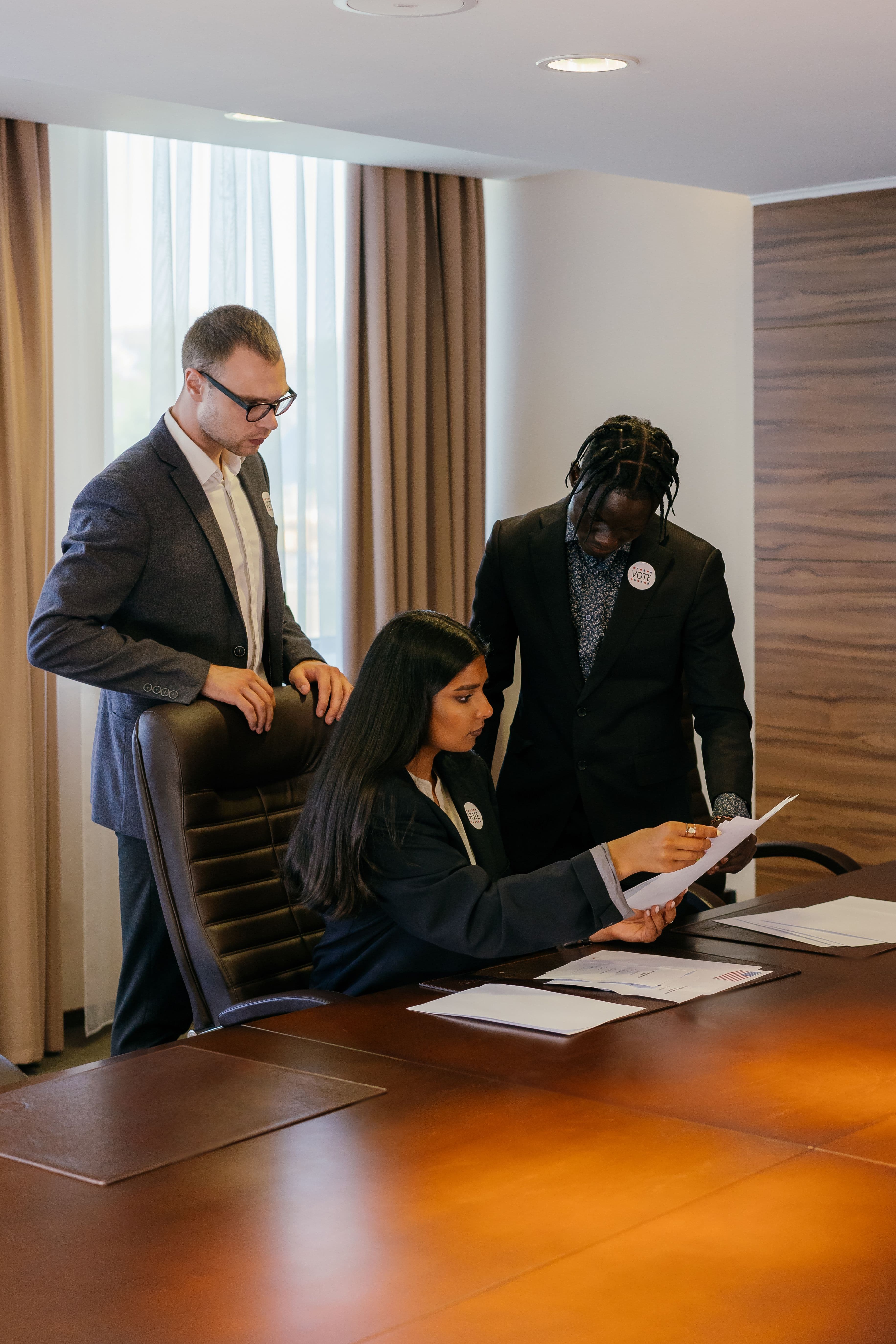 A career consultant reviewing documents and advising two professionals at a desk