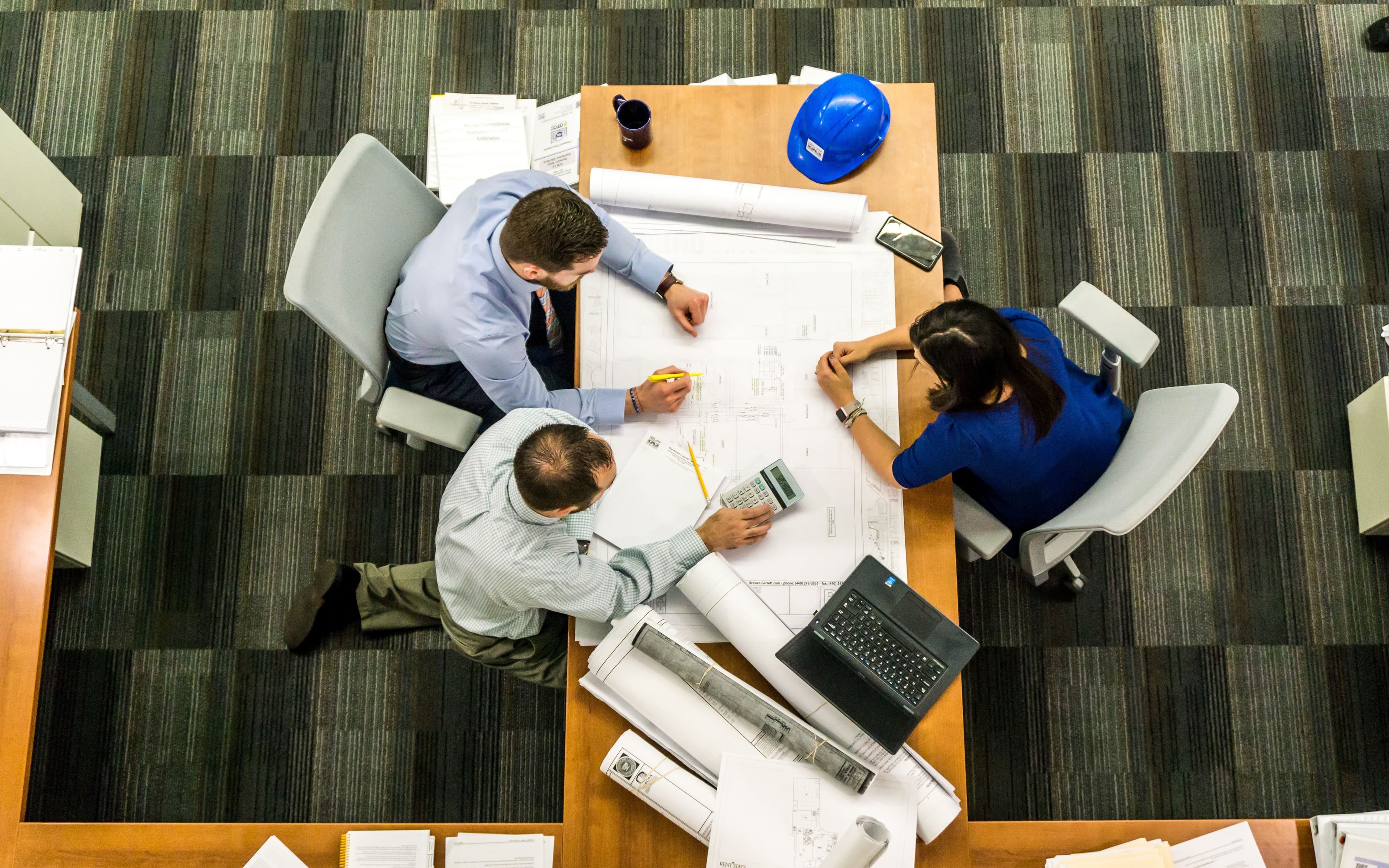 Overhead view of professionals collaborating at a desk with a laptop and documents